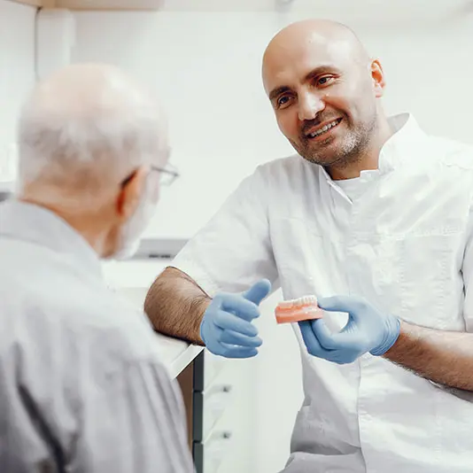 Dentist talking to a patient and holding dentures at Darwenside Dental Practice